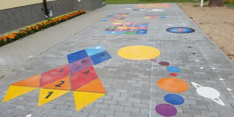 Kolorowe gry plenerowe na placu zabaw: rakieta z liczbami, układ planet i plansza do gry.
