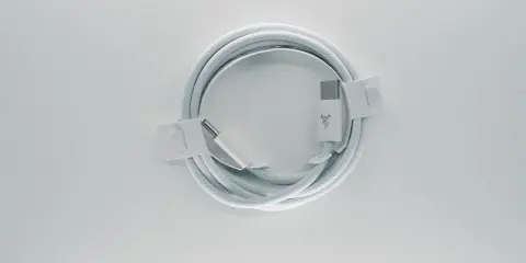 Biały kabel usb typu c, zwinięty w okrąg, z metalowymi końcówkami i logo producenta.