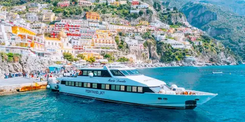 Il Positano Jet attracca al molo, con le case colorate della Costiera Amalfitana sullo sfondo.