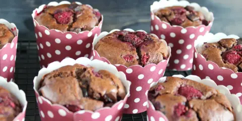 Saftige schokomuffins mit Himbeeren, gebacken in rot-weißen Pünktchen-Förmchen, warten auf ihren Genuss.