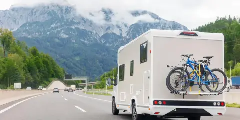 Kamperem nad morze, z rowerami na bagażniku, jedzie autostradą w górach.