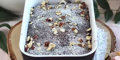 Pyszny brownie z mikrofali, posypany cukrem pudrem i orzechami, w białej ceramicznej formie.