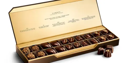 Caja abierta de chocolates finos, "la chuche más cara del mundo", con descripciones de sabores inspirados en elementos naturales.