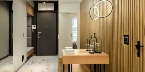 Nowoczesny hol z drewnianą, żebrowaną ścianą, która stanowi świetny pomysł na krzywe ściany. Oświetlenie pierścieniowe i konsola dodają elegancji.