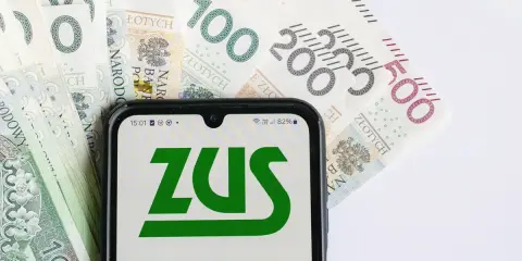 Telefon z logo ZUS na tle polskich banknotów. To symboliczne przedstawienie świadczenia wspierającego punkty, które można zdobyć za aktywność.