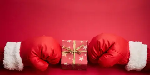Rękawice bokserskie w świątecznym stylu otaczają prezent. Czy to zapowiedź, boxing day co to znaczy?