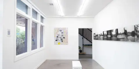 Inside the Atlanta Center for Photography, a white bench sits before a map artwork. Black and white photos line the opposite wall.