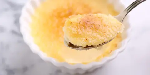 Une cuillère de semoule au lait et aux œufs, avec sa croûte caramélisée dorée, prête à être dégustée.