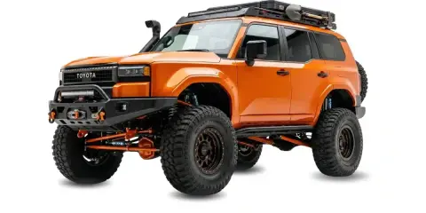 Pomarańczowy Toyota z terenowym wyposażeniem, wyciągarką i bagażnikiem dachowym. Zastanawiasz się, ile kosztuje malowanie auta Raptor?