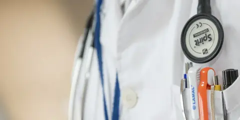 Lekarz w białym fartuchu ze stetoskopem i przyborami w kieszeni. Wczesne wykrycie chlamydii u mężczyzn jest kluczowe dla zdrowia.