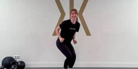 Frau in Sportkleidung macht eine Kniebeuge, bereit für das Skifahren. Krafttraining für die Pisten.