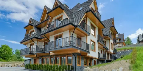 Nowoczesne apartamenty Bachledzki Wierch z drewnianymi elementami i balkonami, otoczone zielenią.