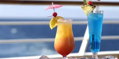 Due cocktail colorati, un tramonto e un blu intenso, decorati con ombrellini e frutta, perfetti per godersi i pacchetti bevande MSC in crociera.