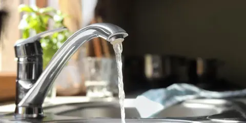 Wasserhahn mit integriertem Durchlauferhitzer, Testsieger. Wasser fließt aus dem Hahn in die Spüle.