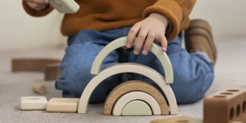 Niño jugando con bloques de madera, creando un arcoíris. Un ejemplo de método Montessori en casa para el desarrollo infantil.