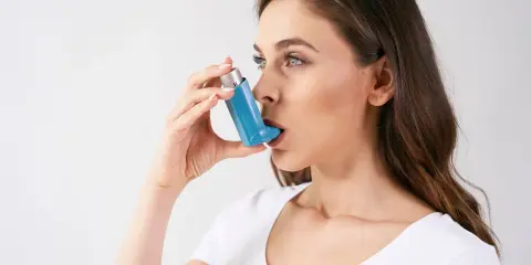 Frau mit Inhalator, der bei Asthma hilft. Hohe Luftfeuchtigkeit kann Symptome verschlimmern.