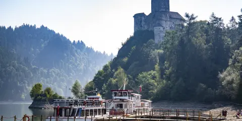 Zamek na skale nad jeziorem, z zacumowanymi statkami wycieczkowymi. Niezapomniane atrakcje Małopolska.