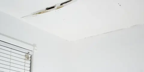 Widoczne pęknięcia na łączeniu sufitu i ściany, świadczące o problemach z konstrukcją lub wilgocią.