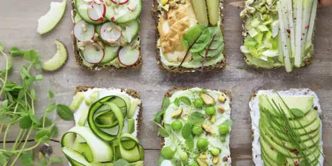 Sześć pysznych kanapek z awokado, ozdobionych warzywami, kiełkami i orzechami. Idealne na zdrowy lunch!
