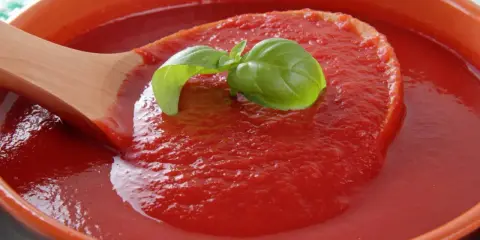 Gęsty, domowy ketchup w ceramicznej misie, nabierany drewnianą łyżką. Idealny przepis na ketchup z bazylią.