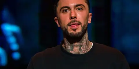 Malik Montana, mój brat, z tatuażami na szyi, w czarnej bluzie z napisem "PLAY".