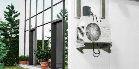 Unité extérieure d'une pompe à chaleur installée sur un mur blanc, à côté d'une maison moderne avec de grandes fenêtres. Comment choisir quelle pompe à chaleur choisir pour votre maison ?