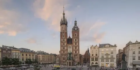 Majestatyczna Bazylika Mariacka góruje nad Rynkiem Głównym w Krakowie. Tłumy spacerują, podziwiając architekturę i atmosferę miasta.