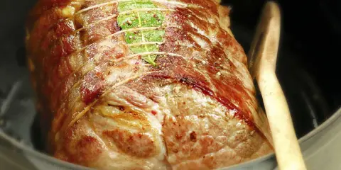 Un rôti de porc cocotte, doré et savoureux, est prêt à être dégusté. Une feuille de laurier orne sa surface.
