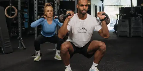 Mann und Frau trainieren Kraftsport mit Kettlebells im Fitnessstudio.