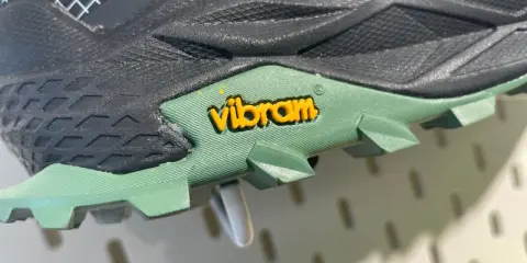 Detailaufnahme einer grünen Vibram Sohle mit gelbem Logo. Mögliche Nachteile: Abnutzung des Profils bei starker Beanspruchung.