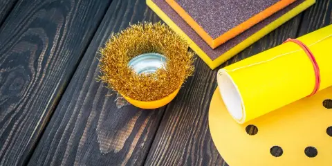 Outils de ponçage : brosse métallique, éponges abrasives et papier de verre pour préparer une surface en polyester avant l'application d'époxy.