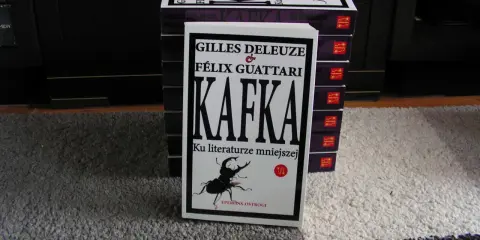 Stos książek z "Kafką" Deleuze'a i Guattariego, z widocznym żukiem na okładce, nawiązującym do prozy Franza Kafki.
