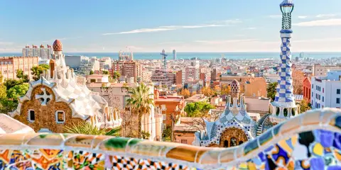 Kolorowe mozaiki i bajkowe budowle w Parku Güell z widokiem na Barcelonę.