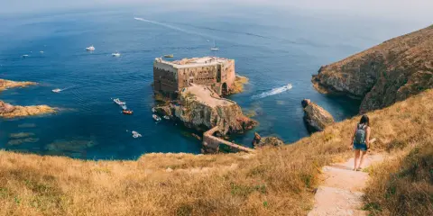 Wanderin auf der Insel Berlenga Grande, Portugal, Leiria. Eine Festung thront im Meer, Boote schaukeln im Wasser.