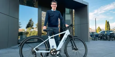 Mężczyzna w okularach stoi obok białego roweru elektrycznego marki Groclin.
