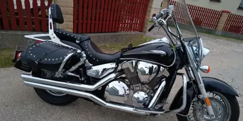Błyszczący, czarny motocykl Honda VTX 1300 z sakwami i oparciem. Dane techniczne tego klasyka są imponujące.