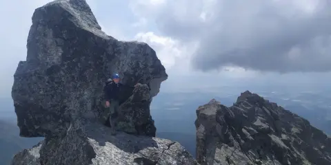 Wspinacz w kasku na skalistym szczycie, podziwiający widok. Tatry poza szlakiem, gdzie każdy krok to przygoda.