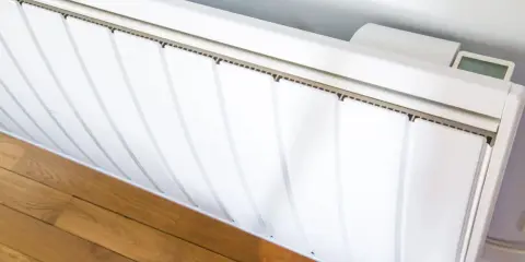 Radiateur électrique blanc installé sur un parquet. Un écran affiche la température. Guide pour comment installer un radiateur électrique.