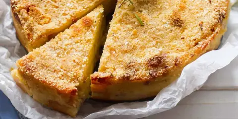 Delizioso gateau di patate dorato e croccante, guarnito con rosmarino fresco. Una fetta è già stata servita.