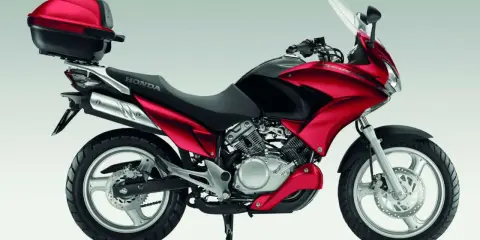 Czerwony motocykl Honda Varadero 125 z kufrem, gotowy na odblokowanie mocy i przygodę.