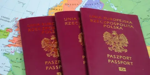 Trzy polskie paszporty leżą na mapie Europy. Czy do Grecji potrzebny jest paszport? Tak, jeśli podróżujesz spoza strefy Schengen.