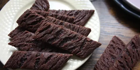 Chokladsnittar recept: Mörka, avlånga chokladkakor med räfflad yta ligger på en ljusgul tallrik. Perfekta till fikat!