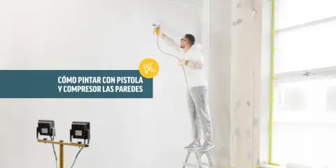 Hombre con traje protector pintando una pared con pistola y compresor.