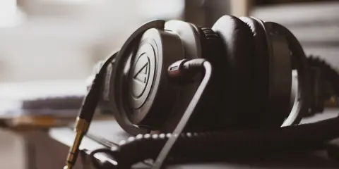 Gros plan sur un casque audio noir, avec son câble spiralé et sa prise jack dorée. La sensibilité du casque audio est palpable.