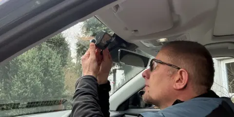 Mężczyzna montuje kamerę samochodową nad lusterkiem wstecznym. Dbałość o szczegóły podczas instalacji zapewnia bezpieczeństwo na drodze.