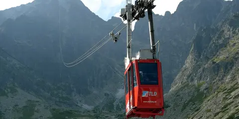 Czerwona kolejka linowa w Tatrach na tle skalistych gór.