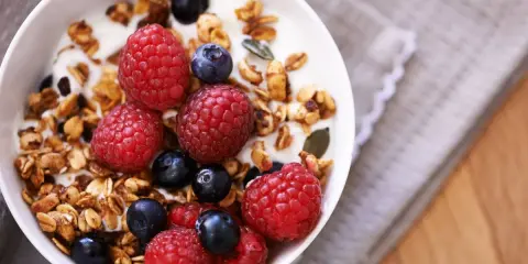 Un tazón de yogur con granola casera, frambuesas y arándanos. Un desayuno saludable y delicioso.