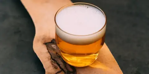 Szklanka złocistego piwa z pianką na drewnianej desce. Zastanawiasz się, ile to litr wina?