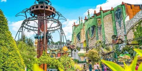 Phantasialand: Kettenkarussell und grüne Fantasiegebäude mit Achterbahn.