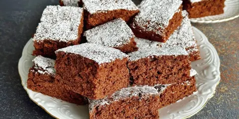 Pyszne, wilgotne ciasto czekoladowe pokrojone w kostkę, posypane cukrem pudrem. Idealne na przepis na ciasto kręcone.